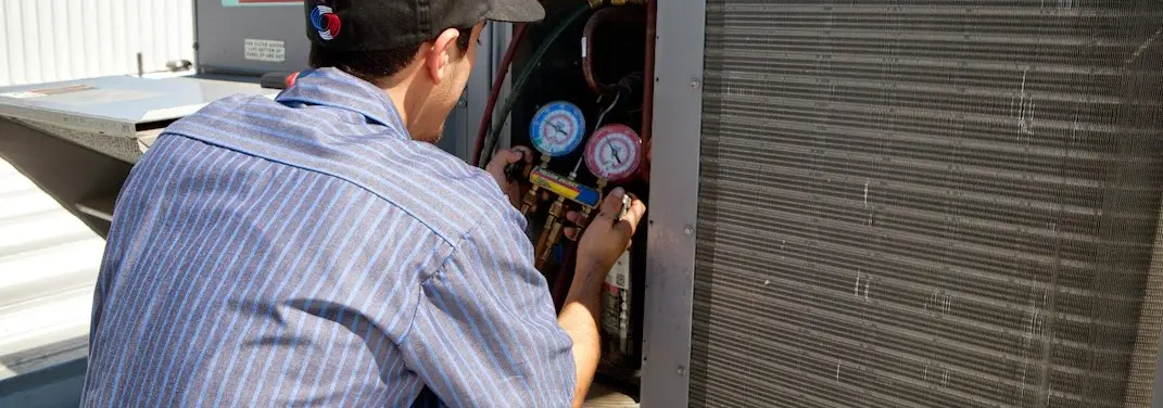 HVAC technician servicing a condenser unit in Westlake